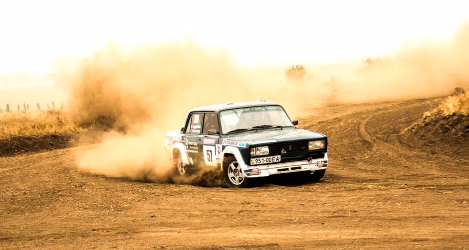 Exciting rally car drifting on a dirt track, creating a cloud of dust. Captured in high-speed action.