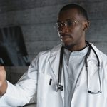professional-doctor-with-eyeglasses-reviewing-an-x-ray-indoo